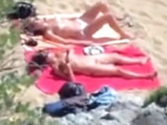 Two nude girls sun bathing on beach.