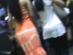 Amateur upskirt video shows a girl in a seductive orange dress.